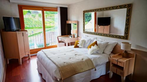 een slaapkamer met een groot bed en een spiegel bij Hôtel Real Nyon by HappyCulture in Nyon
