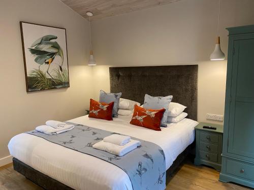 um quarto com uma grande cama branca com almofadas coloridas em Conker Lodge with Hot Tub em Cupar
