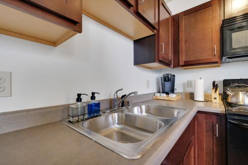 a kitchen with a stainless steel sink and wooden cabinets at Historic Guthrie Coke Lofts, Downtown Louisville in Louisville