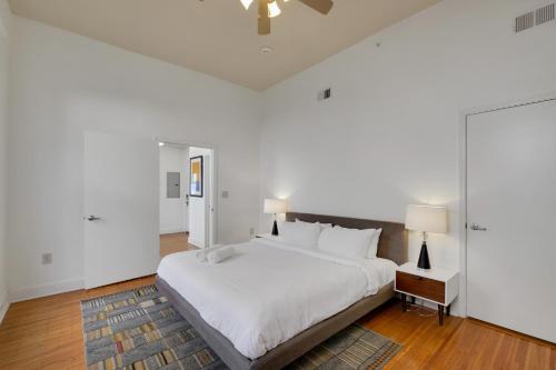 a white bedroom with a large bed with white sheets at Historic Guthrie Coke Lofts, Downtown Louisville in Louisville