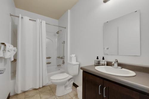 a white bathroom with a toilet and a sink at Guthrie Coke Lofts, Walkable Entertainment in Louisville