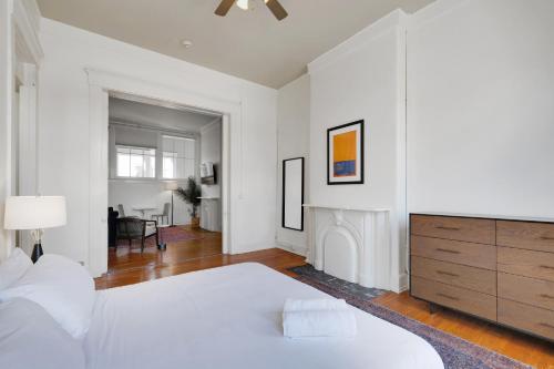 a white bedroom with a large bed and a dresser at Historic Charm In Guthrie Coke Lofts in Louisville