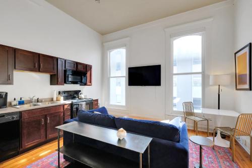 a living room with a blue couch and a kitchen at Historic Guthrie Coke Lofts, Downtown Louisville in Louisville