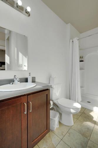 a white bathroom with a sink and a toilet at Historic Guthrie Coke Lofts, Downtown Louisville in Louisville