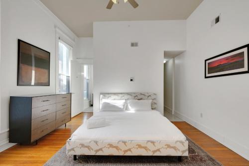 a white bedroom with a bed and a tv at Historic Guthrie Coke Lofts, Downtown Louisville in Louisville