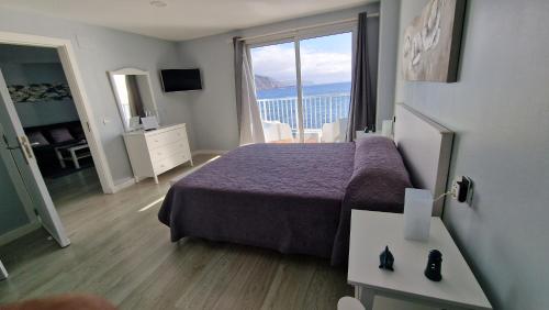 Puerto de la MaderaにあるCrepúsculoのベッドと大きな窓が備わるホテルルームです。