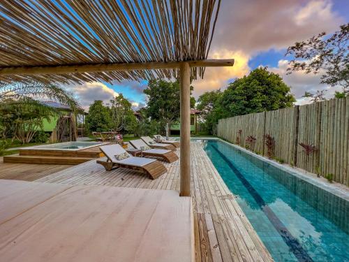 a swimming pool with lounge chairs next to a fence at Riviera Trancoso in Trancoso