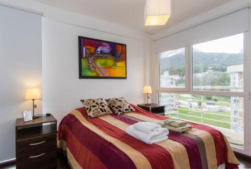 1 dormitorio con cama y ventana grande en Pacífico Apartamentos Ribera en Ushuaia