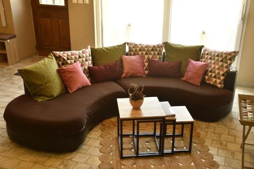 a couch with pillows on it in a living room at AU LOGIS DES CHOUETTES, proche de Verdun et ses champs de bataille in Châtillon-sous-les-Côtes