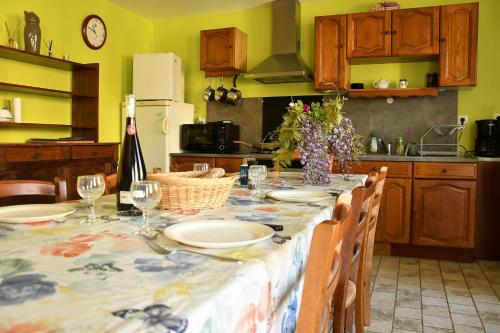 a kitchen with a table with plates and wine glasses at AU LOGIS DES CHOUETTES, proche de Verdun et ses champs de bataille in Châtillon-sous-les-Côtes