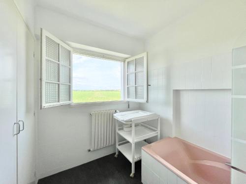 La salle de bains est pourvue d'une baignoire rose et d'une fenêtre. dans l'établissement LA VILLA STE ANNE - Wifi - Plages et bourg de Plonevez à 2 min, à Plonévez-Porzay