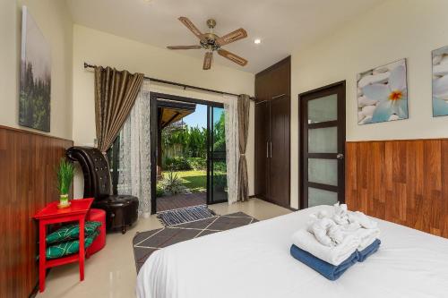 Schlafzimmer mit einem Bett und einer Tür zu einer Terrasse in der Unterkunft VILLA MARAMA | Private Pool | Kokyang Estate by Tropiclook | Naiharn beach in Nai Harn Beach