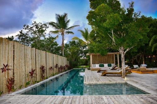 uma piscina num quintal com uma cerca de madeira em Riviera Trancoso em Trancoso