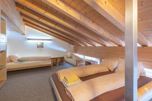 a room with two beds in a loft with wooden ceilings at Appartmenthaus Bergfreund in Fiesch