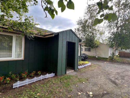 a green house with a door in a yard at Nunaka Valley Cottage in Anchorage