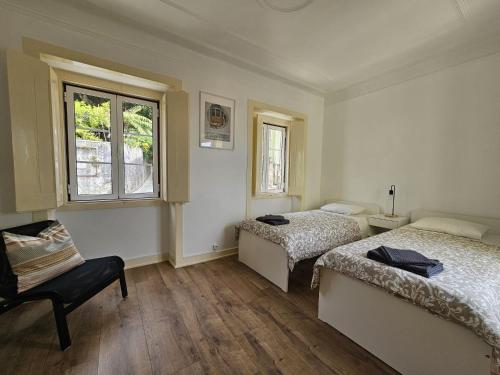 a bedroom with two beds and a chair and a window at Maria Saudade Apartamento in Sintra