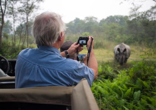 Ein Mann fotografiert einen Elefanten mit einer Kamera. in der Unterkunft Tiger Tops Karnali Lodge in Bardiyā