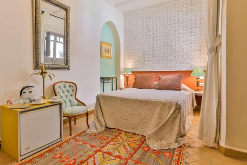 una camera con letto, specchio e sedia di Riad Dar Saad - Hammam & Spa a Marrakech