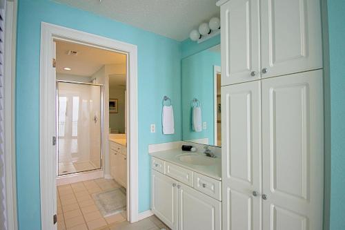 ナバーにあるSunsational Pearl of the Seaの白い洗面台と鏡のあるバスルーム