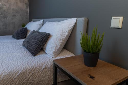 a bed with pillows and a table with a plant on it at Kalniem Pāri Guest House 