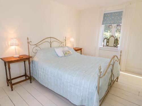 a white bedroom with a bed and a window at Gorphwysfa in Beaumaris