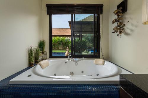 uma banheira branca num quarto com uma janela em VILLA MARAMA | Private Pool | Kokyang Estate by Tropiclook | Naiharn beach em Praia de Naihan