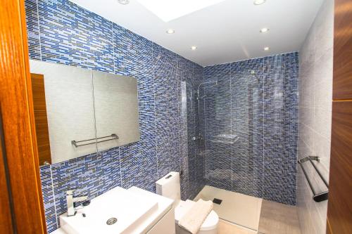 uma casa de banho com um lavatório e um chuveiro com azulejos azuis em 228 - Casa Luca by Villas Now Ltd em Playa Blanca