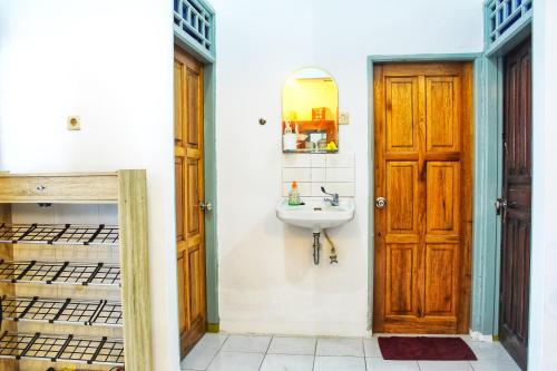 KJ Purple House Senggigi في سينغيغي: حمام مع حوض وباب خشبي