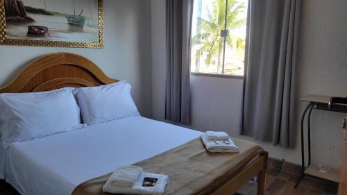 a bedroom with a bed with two towels on it at Hospedagem Clã dos Couto - Pousada in Saquarema