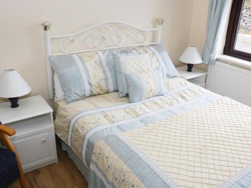 a bedroom with a bed with blue and white sheets and pillows at Daffodil Cottage in Grange