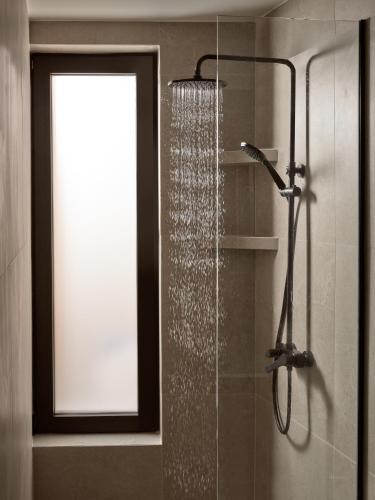 a shower with a glass door and a window in a bathroom at Salita - Comfort Living Apartments in Zakynthos Town