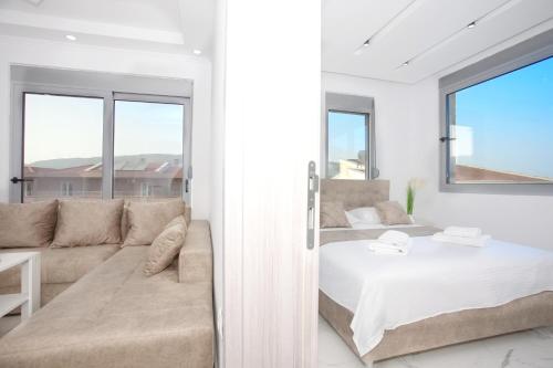 - une chambre blanche avec un lit et un canapé dans l'établissement NESI Apartments, à Ulcinj