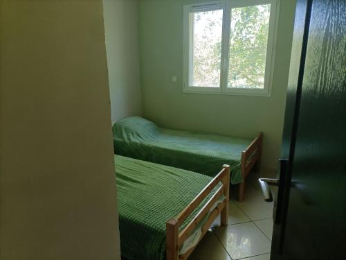 ein kleines Zimmer mit 2 Betten und einem Fenster in der Unterkunft La maison dans les noyer in Sainte-Eulalie
