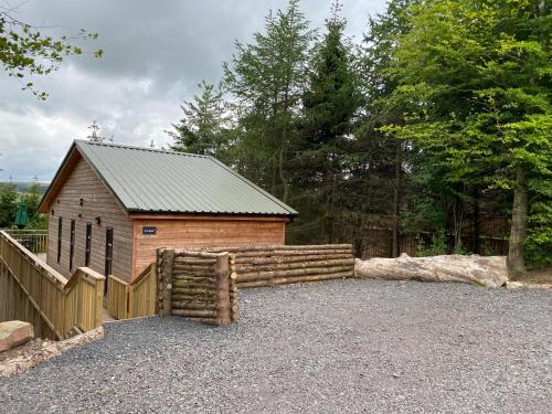 a small building with a fence next to a wooden fence at Holly Berry Lodge with Hot Tub in Cupar