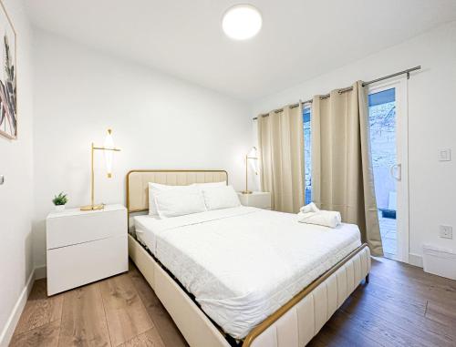 a white bedroom with a large bed and a window at Modern 2BR Oasis - Cal-Cal in Calabasas
