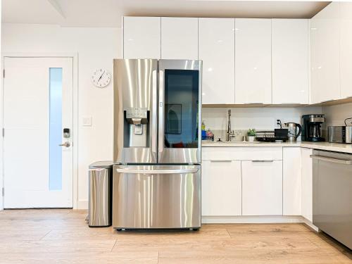 a kitchen with white cabinets and a stainless steel refrigerator at Modern 2BR Oasis - Cal-Cal in Calabasas