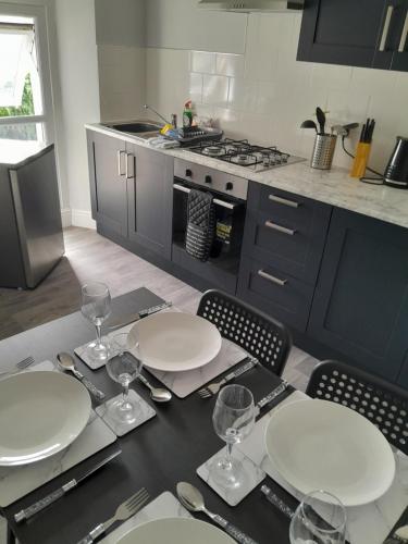 a kitchen with a table with plates and wine glasses at Conveniently located, newly refurbished flat (sleeps 4) in Pembrokeshire