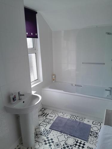 Baño blanco con bañera y lavamanos en Conveniently located, newly refurbished flat (sleeps 4) en Pembrokeshire