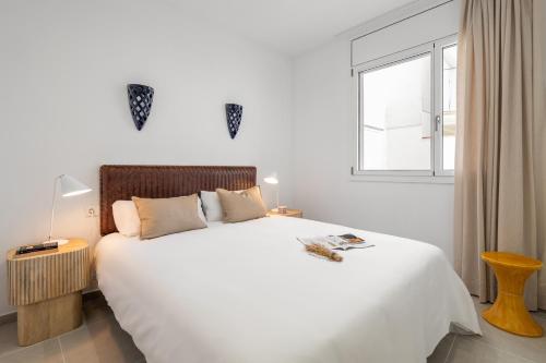 Un dormitorio con una gran cama blanca con ventana. en Calella Apartments by Olala Homes, en Calella