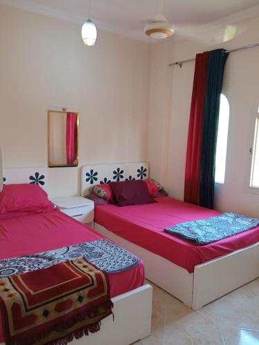 two beds in a bedroom with red and blue sheets at الغردقه البحر الاحمر مبارك 6 in Hurghada
