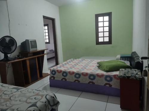a bedroom with two beds and a television in it at Pousada em Mongaguá Kali in Mongaguá