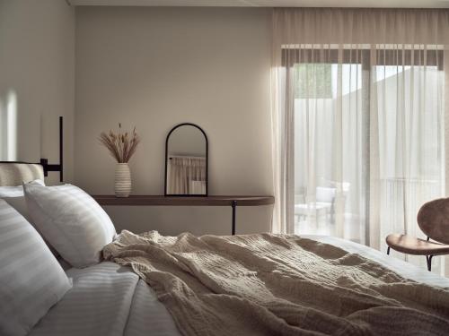 a white bedroom with a bed and a window at Salita - Comfort Living Apartments in Zakynthos Town