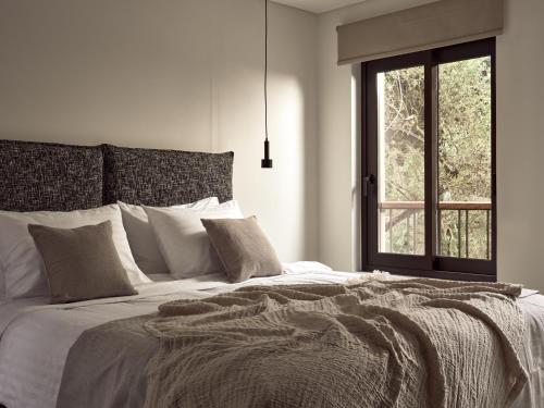 a white bedroom with a large bed with a window at Salita - Comfort Living Apartments in Zakynthos Town