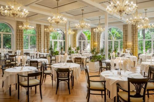 a dining room with white tables and chairs and chandeliers at Villa Bavaria in Merano