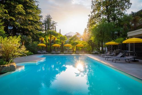una piscina con sombrillas, mesas y sillas en Villa Bavaria en Merano