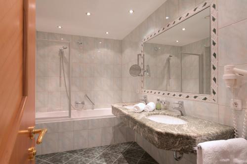 a bathroom with a sink and a tub and a mirror at Hotel Post in Sankt Anton am Arlberg