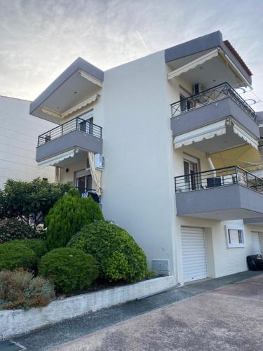 een wit appartementencomplex met balkons en struiken bij ART-appart sea view in Kallithea