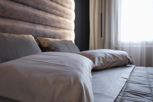 Cama con sábanas blancas y almohadas junto a una ventana en Golden Island Resorts, en Atenas