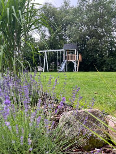 a garden with a playground and purple flowers at Gandro lizdas in Lekėčiai