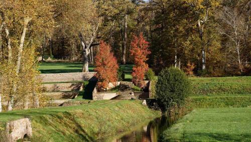 a garden with a river and trees and grass at Château de La Rivière in Pontgouin